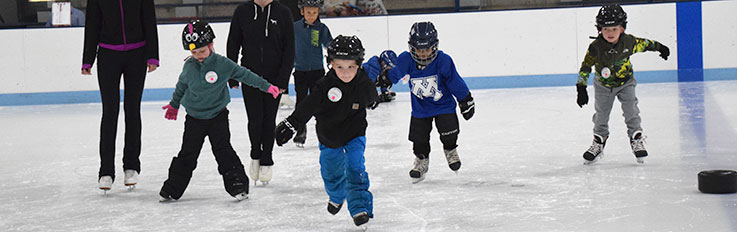 Kids skating on ice with instructors