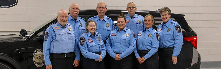 Group of officers in blue in front of police squad