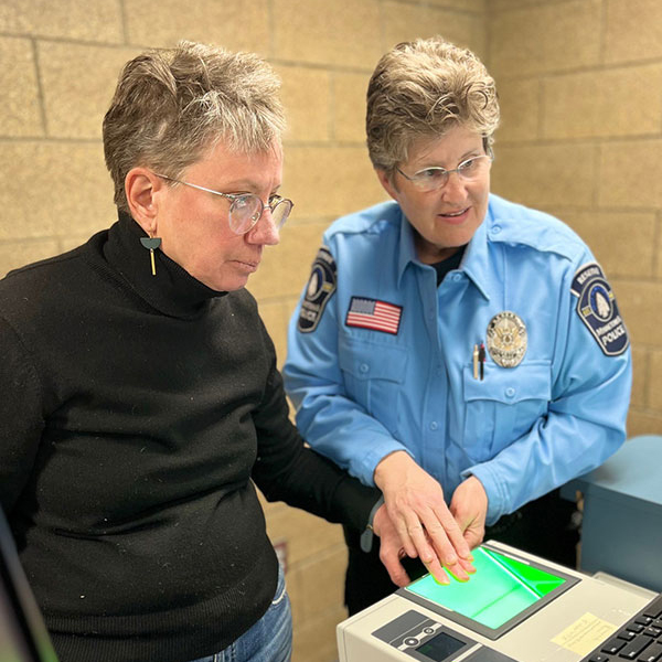 officer helping woman in black shirt with fingerprinting