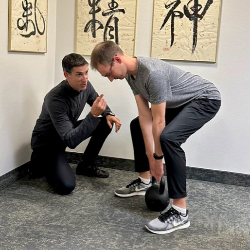 Man talking to man lifting kettleball