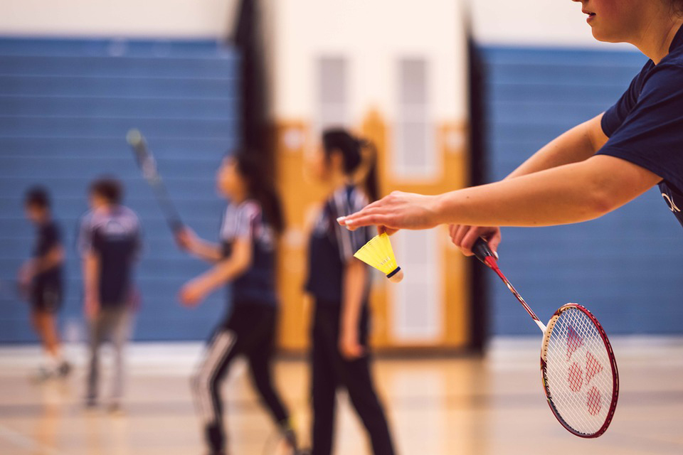 Hand holding badminton shuttlecock and racket