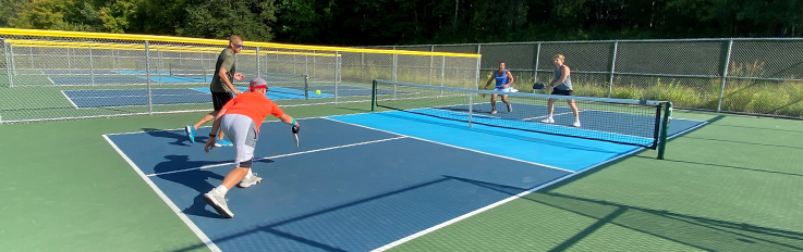 Four men playing pickleball on outdoor court