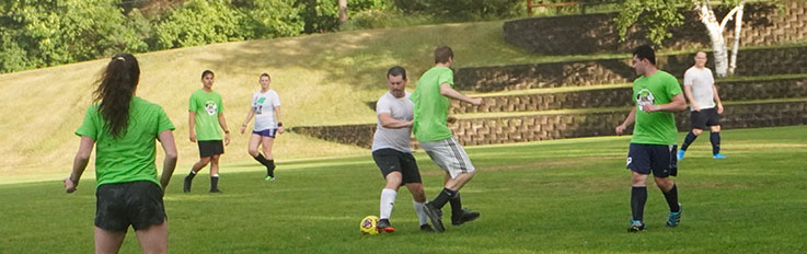 People in green and white shirts playing soccer