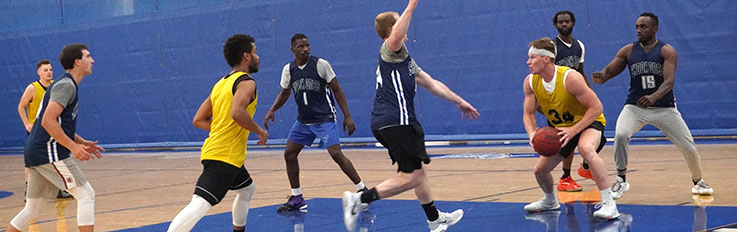 Large group of men playing basketball on indoor court