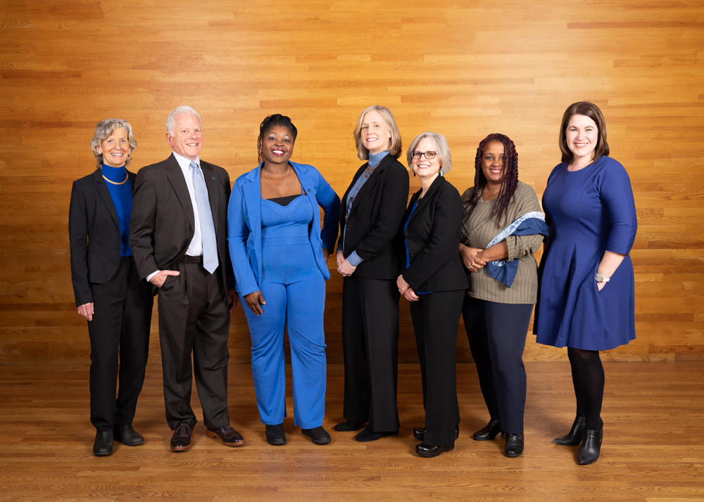 Seven people in blue smiling in line