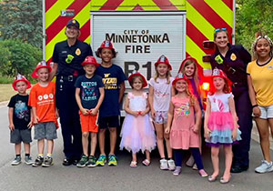 Two firefighters with kids in front of truck