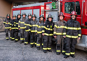 Large group of firefighters lined up along truck