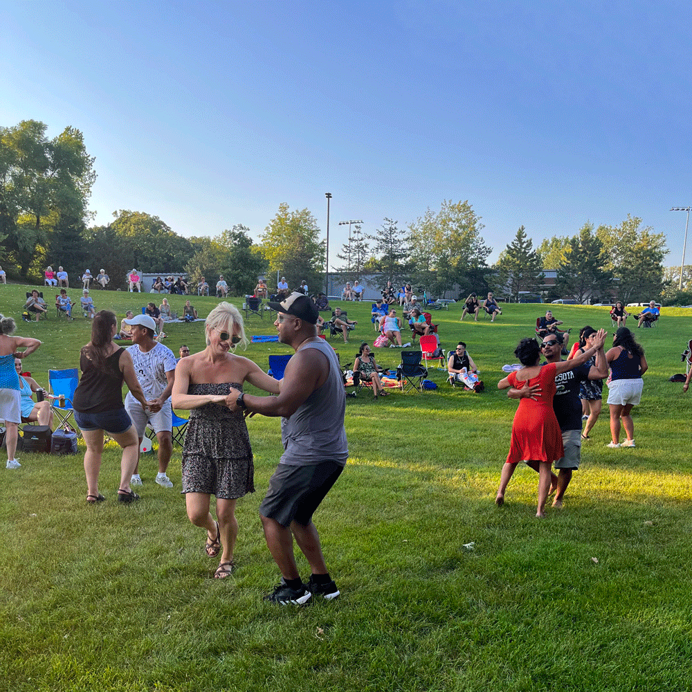 Several people dancing to live music during Music in the Park