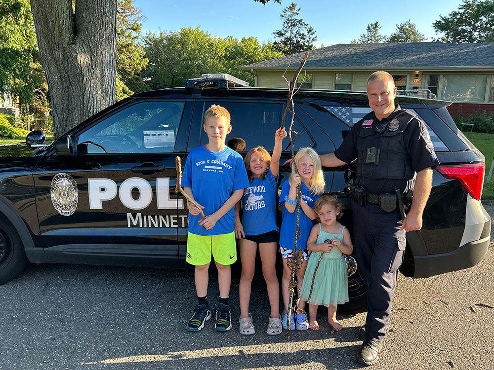 Officer with four kids in front of a squad car