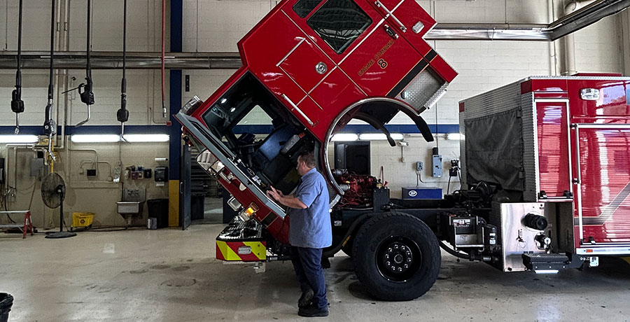 Man standing in front of red fire truck with hood lifted