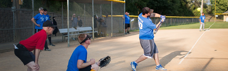 Batter swinging at softball with catcher behind homeplate