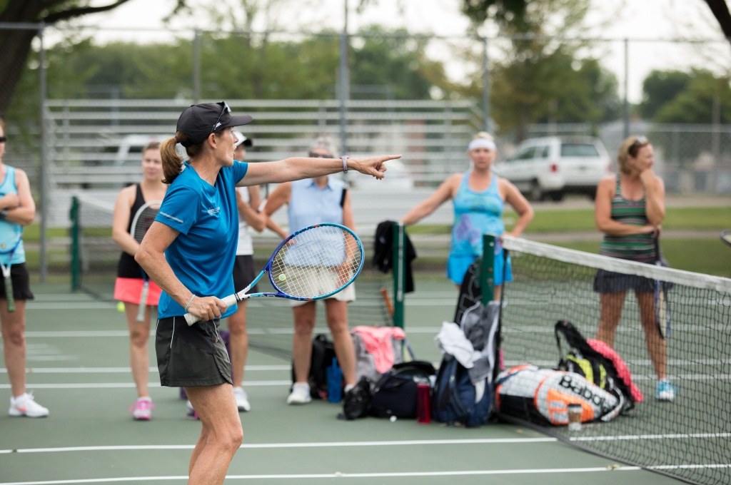 Woman holding tennis racket leading instruction